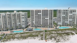 A high-rise hotel with multiple balconies, a swimming pool area, and a beach view.
