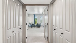 A hallway with white doors leading to a room with two chairs and a small table. - The Bridle is Right | Saltwater Pool | Backyard Games (Mesa)