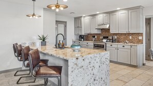 A modern kitchen with white cabinets, a granite island, and stainless steel appliances. - The Bridle is Right | Saltwater Pool | Backyard Games (Mesa)