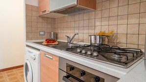A kitchen with a gas stove, oven, and a built-in washing machine. - Casa Vacanza La Rosa (Giardini Naxos)