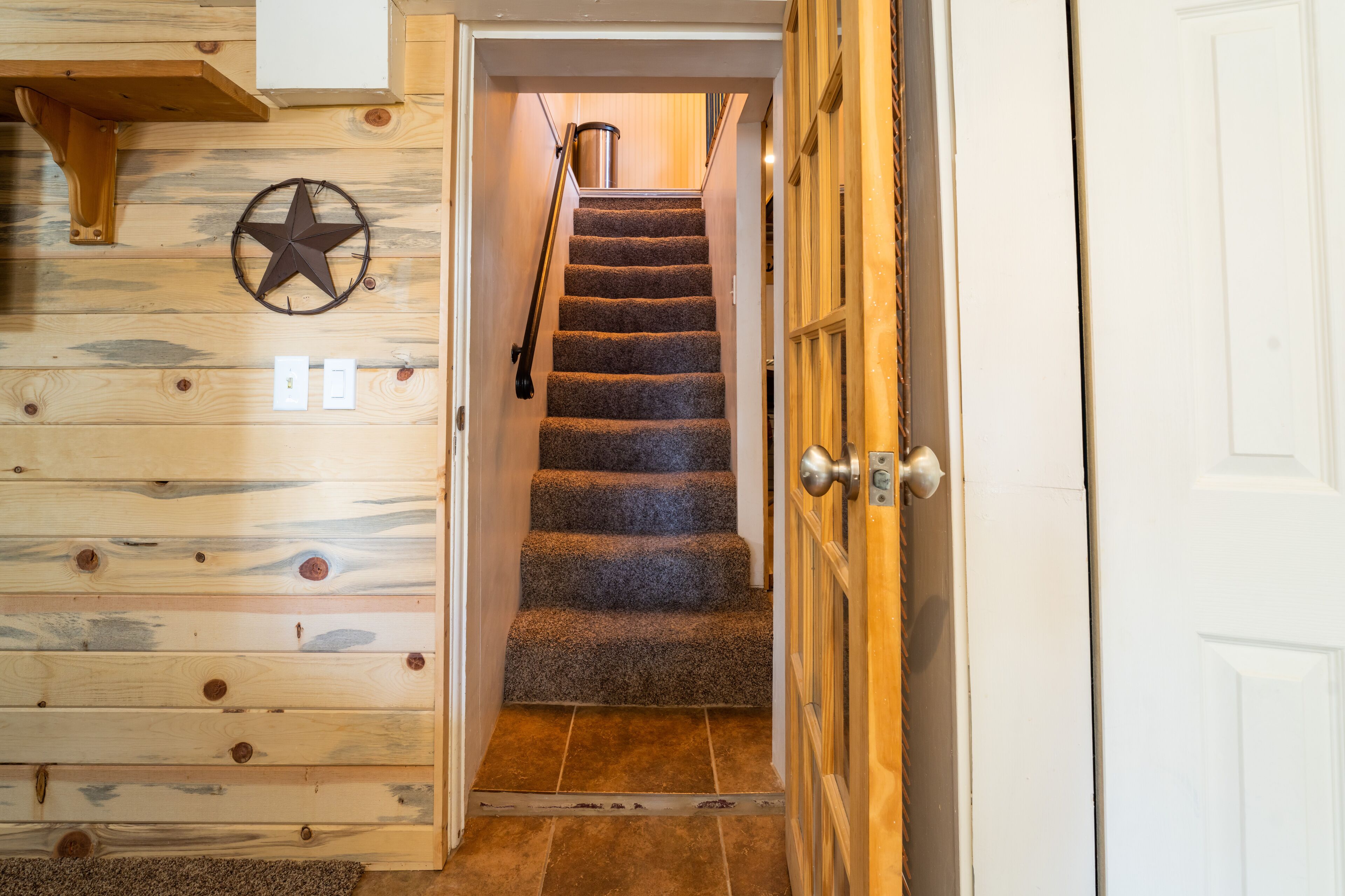 A wooden interior with a carpeted staircase and a star decoration on the wall.