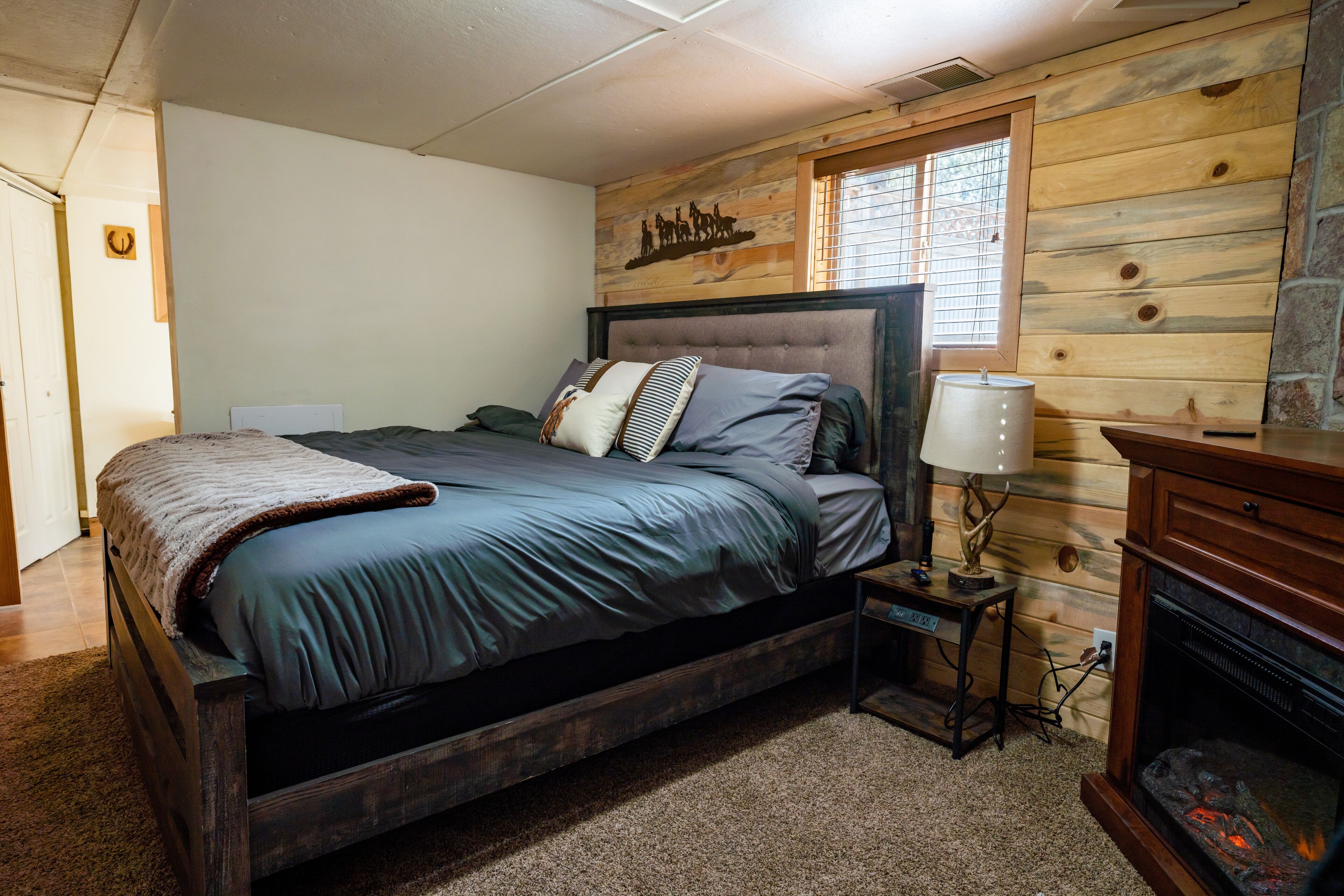 A bedroom with a large bed, a nightstand, a lamp, and a fireplace.