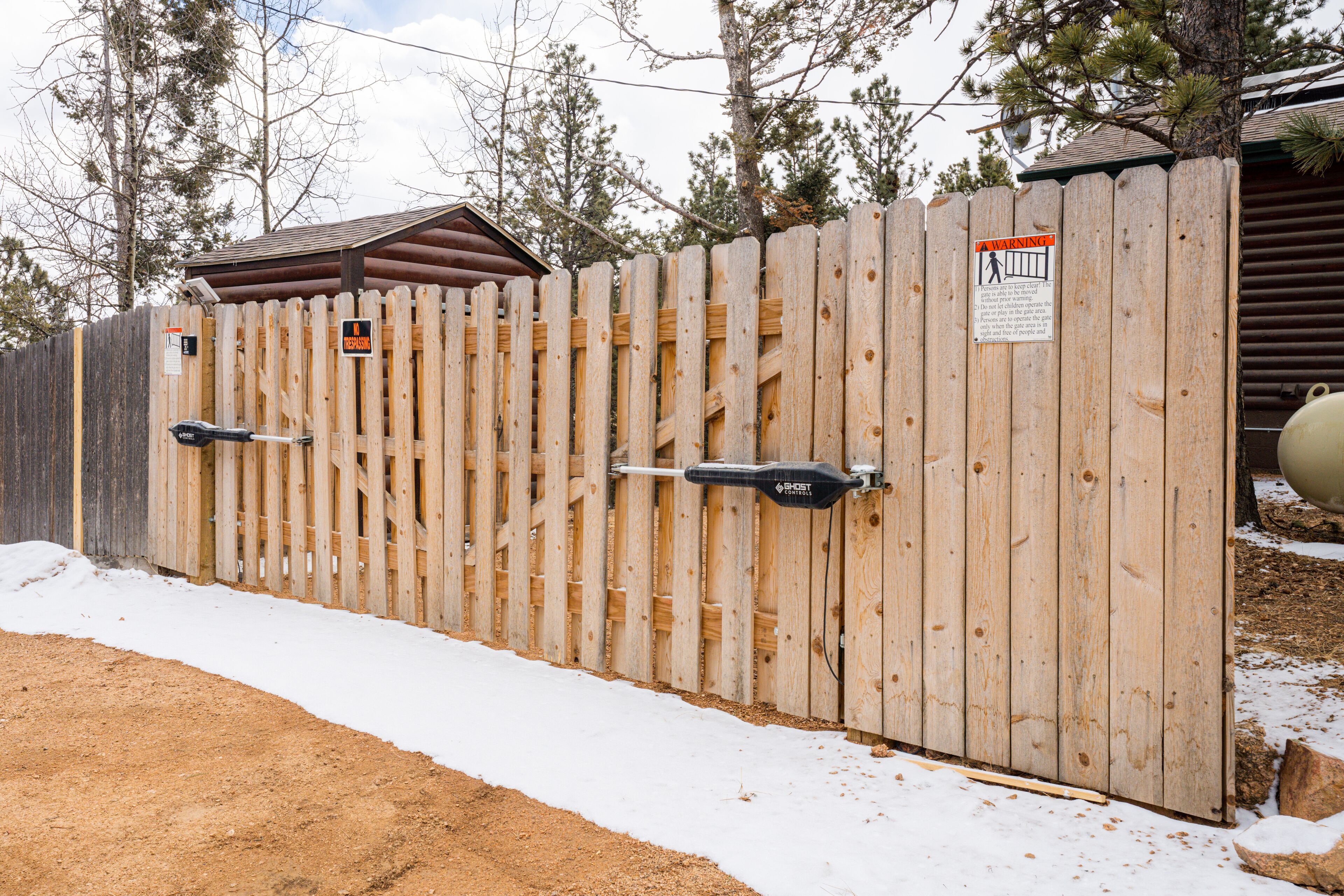 A wooden fence with a warning sign and a metal gate.