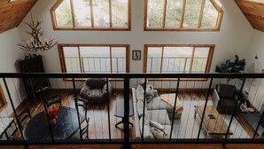 Un'ampia stanza in stile loft con soffitti alti e grandi finestre, un'accogliente area salotto con divano e poltrone, e un tavolo da pranzo con sedie.