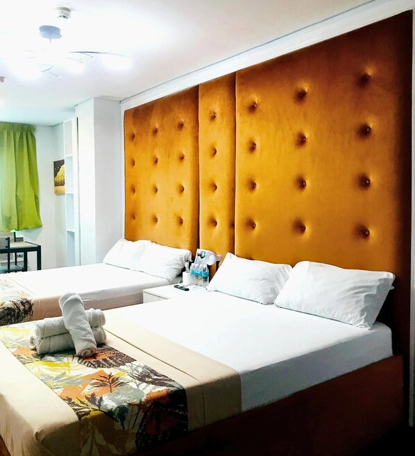A hotel room with two beds, a wooden headboard, white bedding, and a small table with a chair. - Haeinsa Condotel (Quezon City)