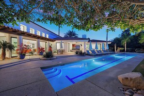A poolside area with a swimming pool, lounge chairs, and a patio with outdoor seating.