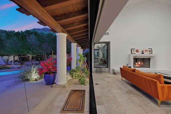 A modern outdoor living area with a fireplace, seating, and potted plants.