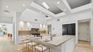 A modern kitchen with a large island, white cabinetry, and a black refrigerator.