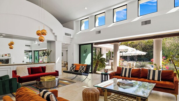 A spacious living area with a large glass table, multiple seating options, and a view of the outdoor patio.