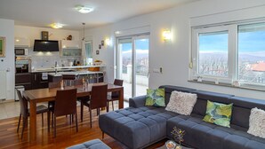 A modern apartment with a dining area, kitchen, and living room with a sofa and large windows. - Stunning home in Svib with house a panoramic view (Svib)