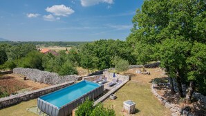 A swimming pool with stone walls, surrounded by trees and a view of the countryside. - Stunning home in Svib with house a panoramic view (Svib)