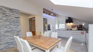 A modern kitchen with white cabinets, a wooden dining table, and white chairs. - Stunning home in Svib with house a panoramic view (Svib)