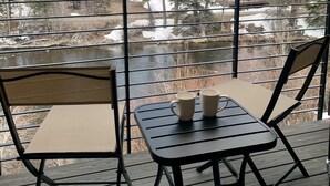 A deck with two chairs and a table, overlooking a river and a mountainous landscape. - New! Luxury Riverfront Retreat with Mountain Views (Silverthorne)