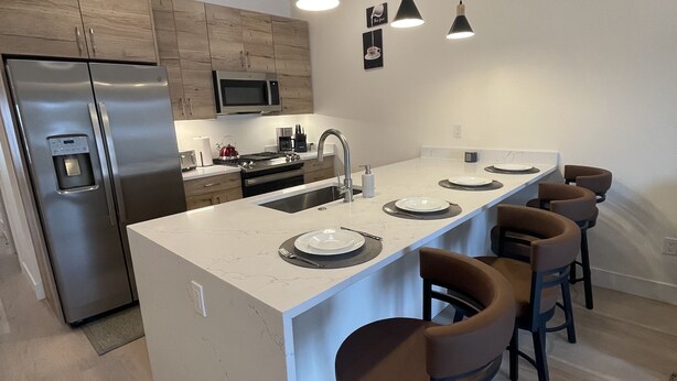 A modern kitchen with a central island, stainless steel appliances, and bar stools. - New! Luxury Riverfront Retreat with Mountain Views (Silverthorne)