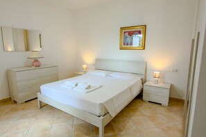 Ein ordentlich eingerichtetes Schlafzimmer mit Bett, Nachttischen, Kommode, Spiegel und einem gerahmten Bild an der Wand.