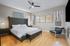 Un dormitorio moderno con cama, mesitas de noche, ventilador de techo y obras de arte en las paredes.