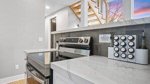 A modern kitchen with a built-in oven, a stove, and a countertop with a spice rack. - The Fairchild Haus | 30 Acres, Sauna, EV Charger (Logan)