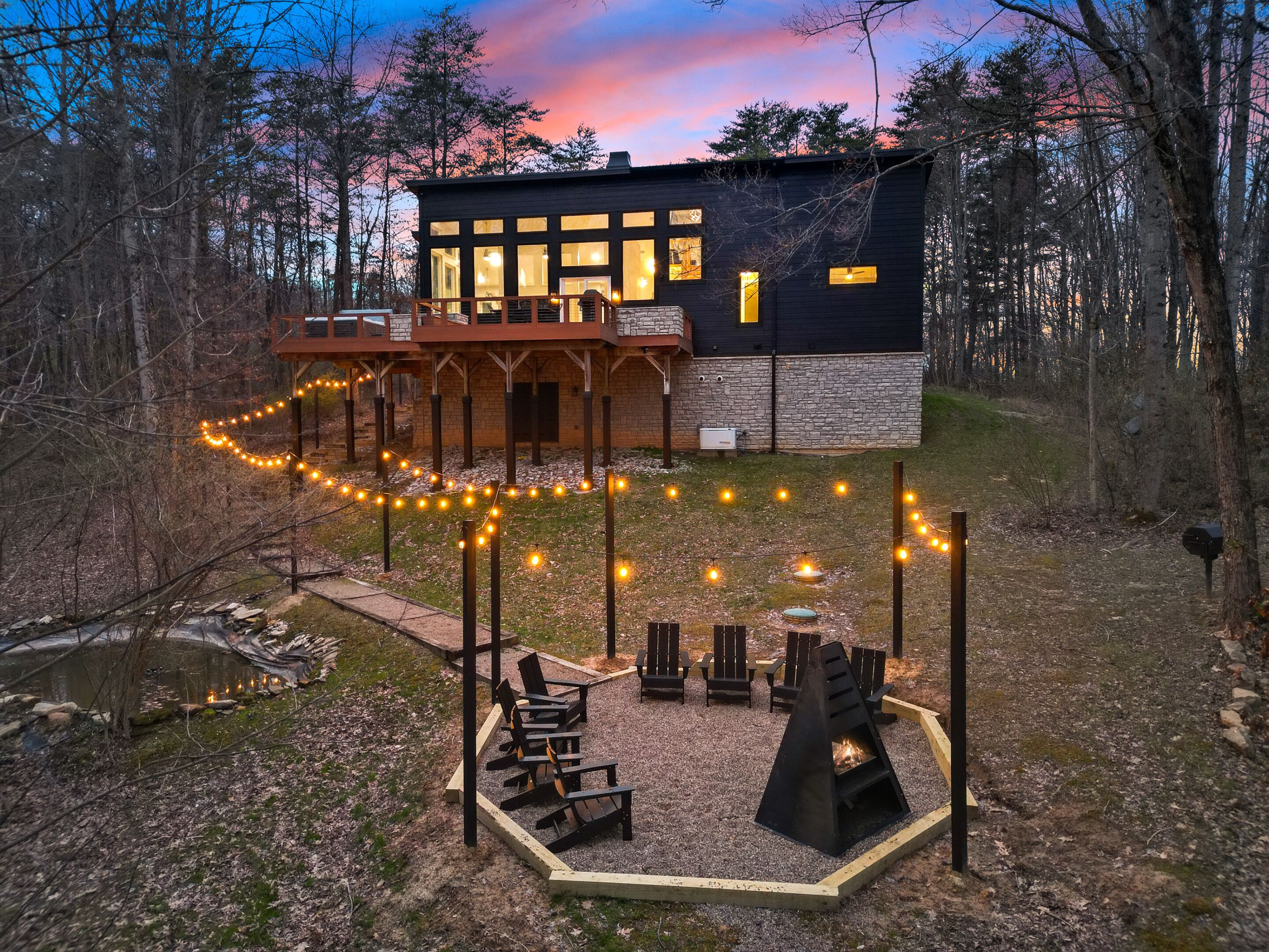 A modern house with a deck, outdoor seating, and a fire pit.