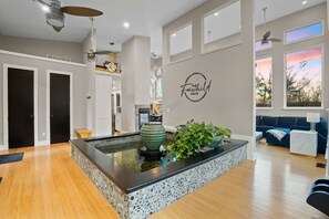 A modern interior with a central water feature, a living area with a sofa, and a wall with a logo.