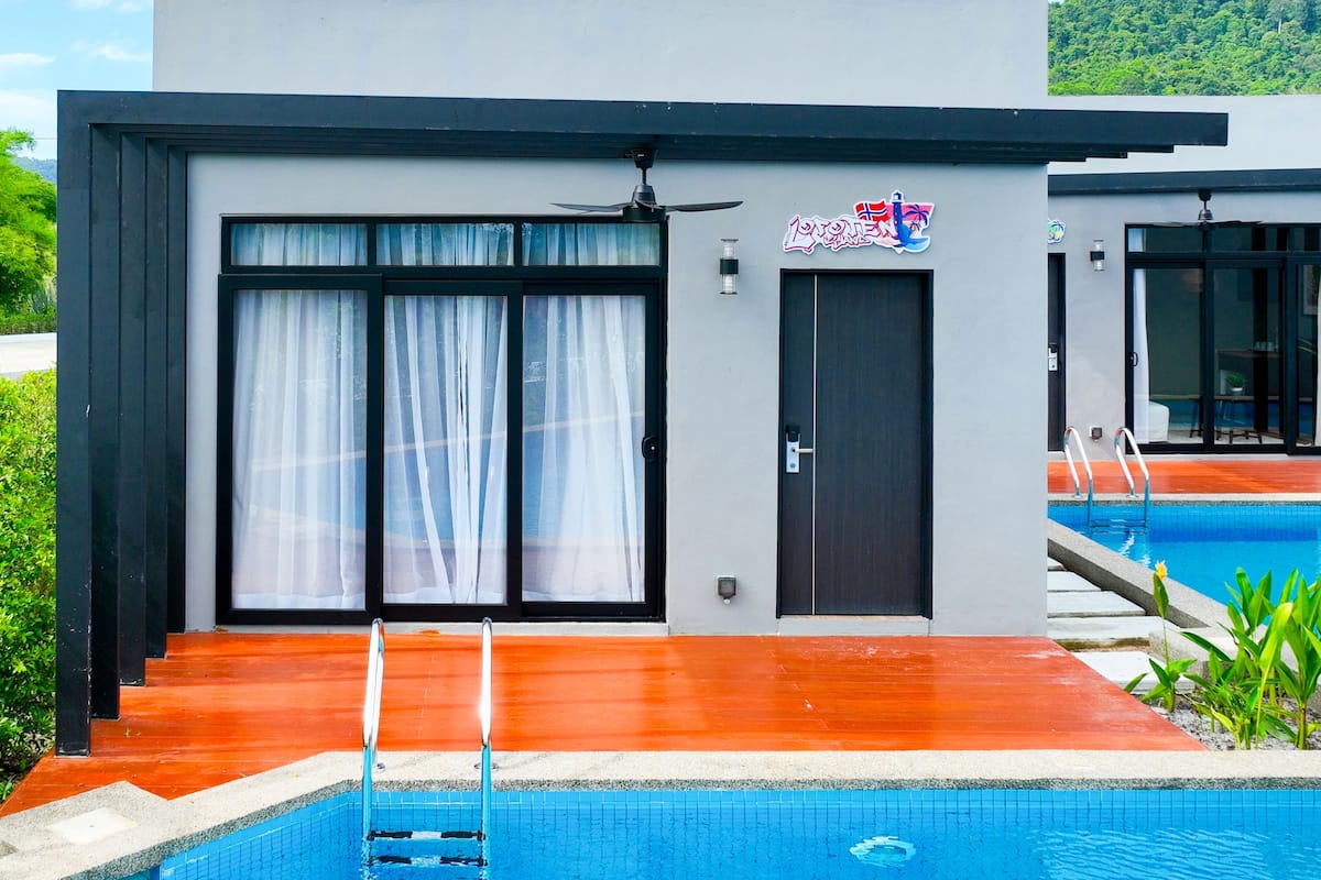 Een modern gebouw met een zwembad, voorzien van een groot schuifglazen raam en een deur met een bord erboven.