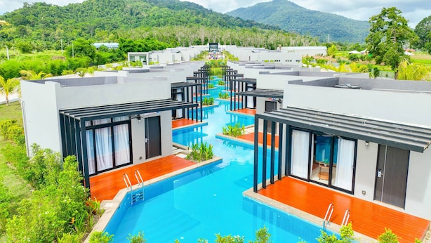Un hôtel moderne doté de plusieurs piscines, entouré d’une végétation luxuriante et de montagnes.