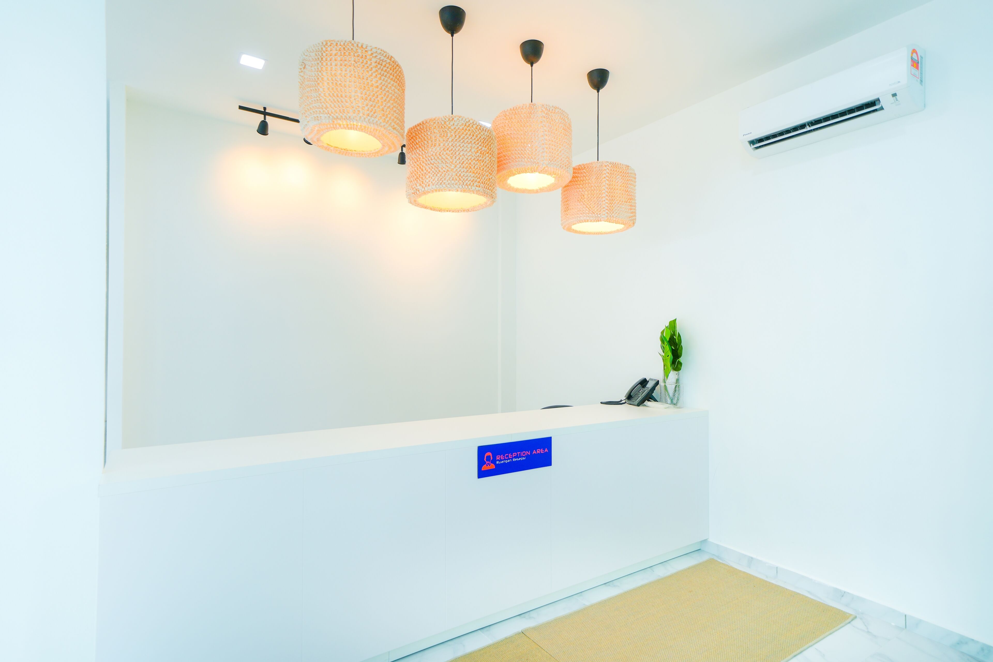 A reception area with a white counter, a reception desk, and three hanging pendant lights.