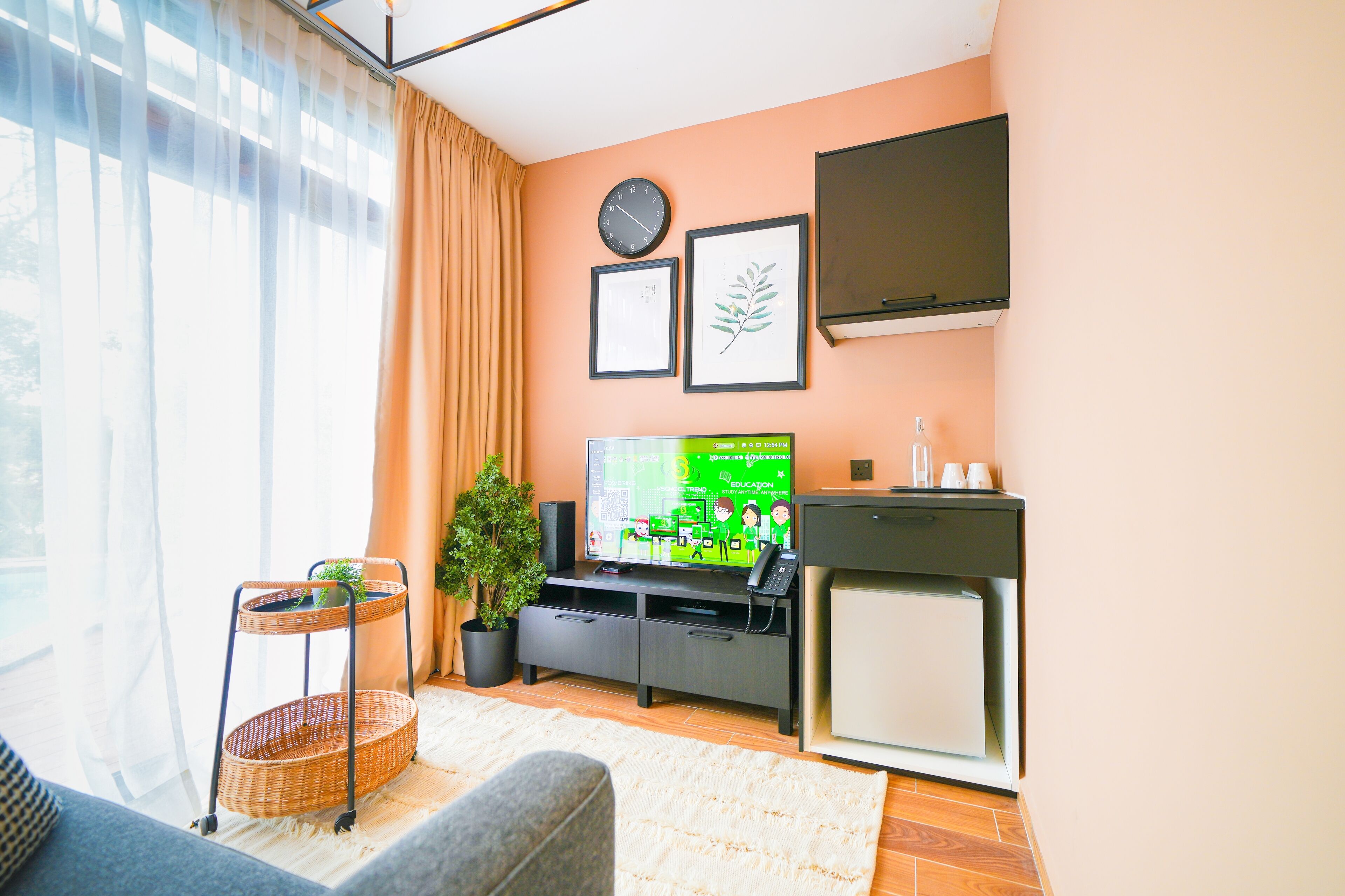 Una sala de estar con televisor, un reloj y cuadros en la pared.