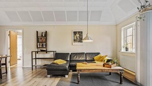 Ein modernes Wohnzimmer mit Ledersofa, Couchtisch aus Holz und Bücherregal.