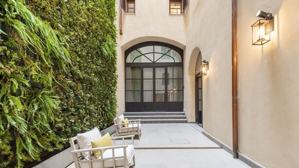 A courtyard with a white bench, a green wall, and a building entrance with arched windows and a door. - Lovely apartment for 10 people with A/C, WIFI, hot tub, TV and balcony (Florence)