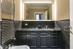 A bathroom with a black marble countertop, a white sink, and a large mirror above the vanity.