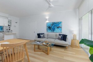 Ein modernes Wohnzimmer mit einer Couch, einem Couchtisch und einem Essbereich mit Stühlen.