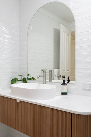 A bathroom with a white sink, a mirror, and a wooden vanity.