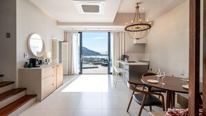 A modern kitchen with a dining area, a view of the sea, and a staircase leading to an upper level. - Busan Nunuhouse Poolvilla Pension (Busan)