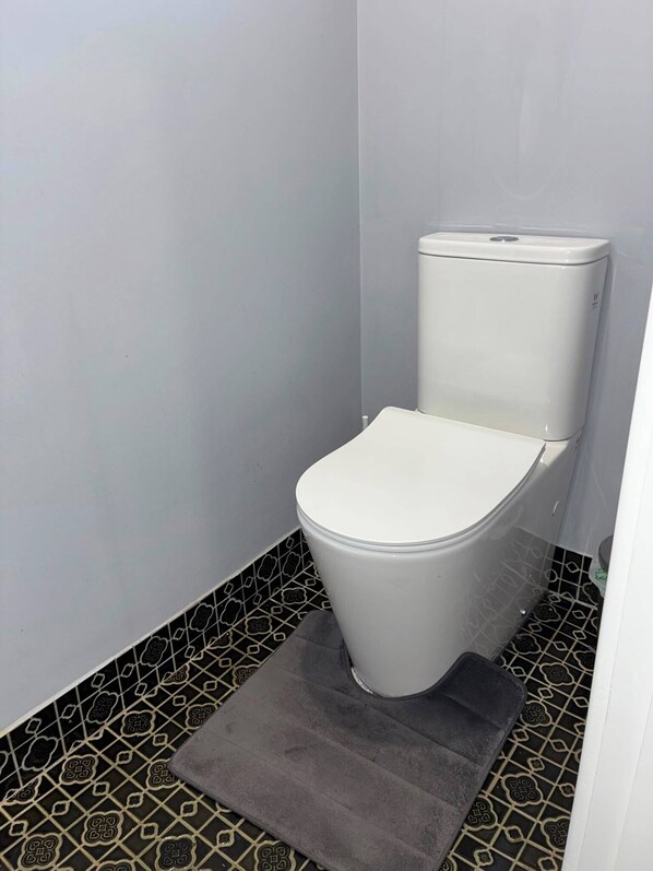 Un inodoro pequeño y blanco en un baño con baldosas en blanco y negro en el suelo.
