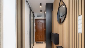 Un couloir doté d’un plancher en bois, d’un miroir à cadre noir et d’une porte ornée de motifs décoratifs.