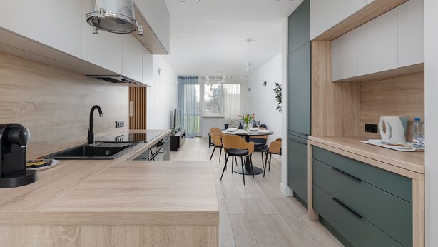 Une cuisine moderne dotée d’un îlot central, d’un coin repas avec des chaises et d’une vue sur l’extérieur.