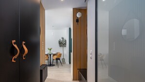 Un intérieur moderne avec un plancher en bois, un coin repas comprenant des chaises et une table, et un espace cuisine avec des placards et un comptoir.