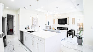 A modern kitchen with white cabinetry, a central island, and pendant lighting.
