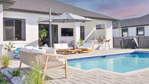 A backyard with a swimming pool, outdoor furniture, and a covered patio area.