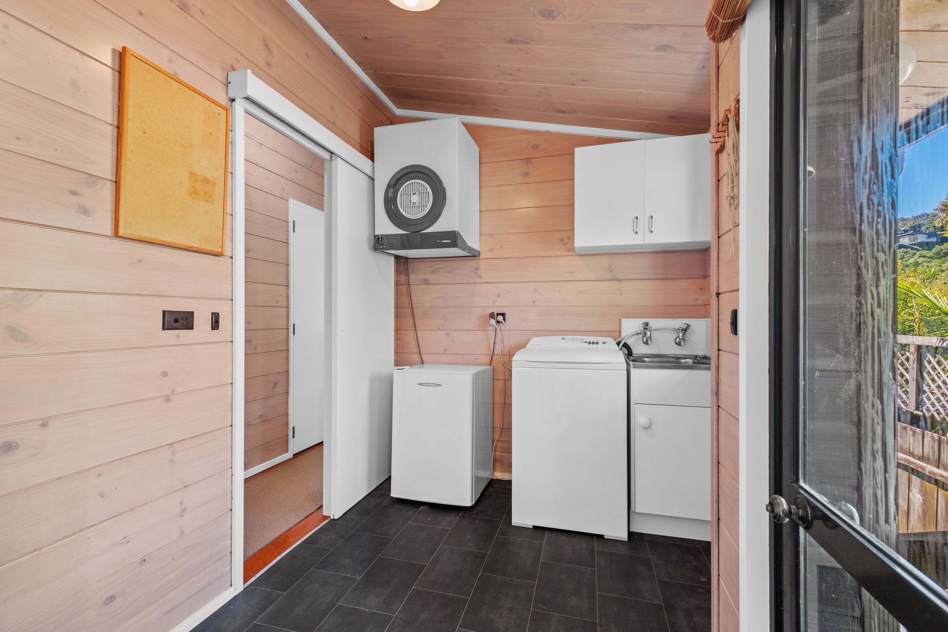 A compact kitchen with a washing machine, a small refrigerator, and a sink.