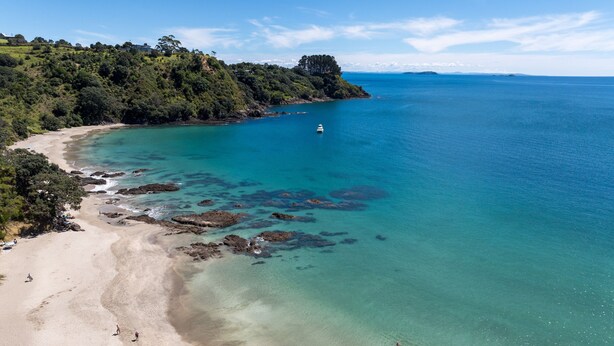 An aerial view of a coastal area with a sandy beach, rocky shoreline, and dense greenery. - Miro Beach House at Palm Beach (Waiheke Island)