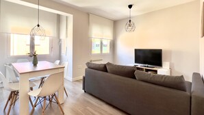 Un salon moderne avec un canapé gris, un plancher en bois et un téléviseur à écran plat.