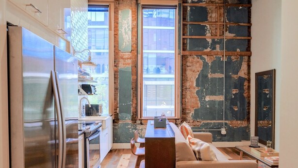 Una cocina moderna con un refrigerador grande, un lavamanos y una zona de comedor con sofá y mesa.