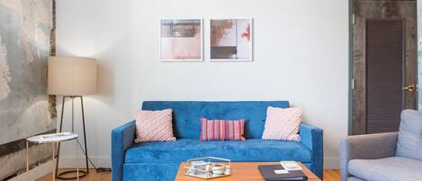 Una sala de estar moderna con un sofá azul, una mesa de centro de madera y una lámpara de pie.