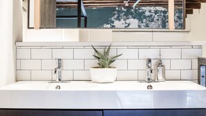 A modern kitchen with a white countertop, two stainless steel faucets, and a potted plant. - Spacious Loft, 2 Blocks from Broadway! (Loft 302) (Nashville)
