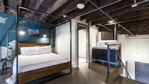 A modern bedroom with a bed, a desk, and a bathroom visible through an open door. - Spacious Loft, 2 Blocks from Broadway! (Loft 302) (Nashville)