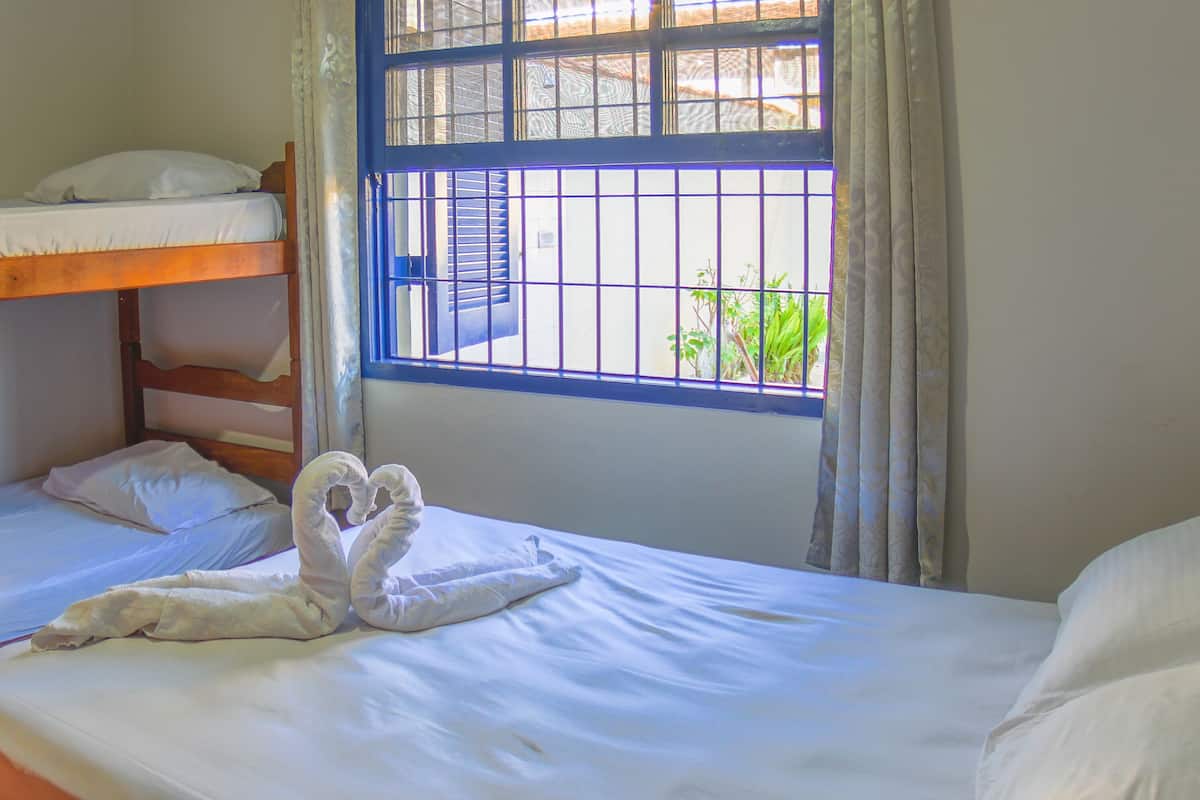 A room with two bunk beds, a window with bars, and a towel art on the lower bunk.