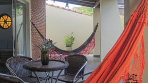 A covered patio area with wicker furniture, a hammock, and a potted plant.