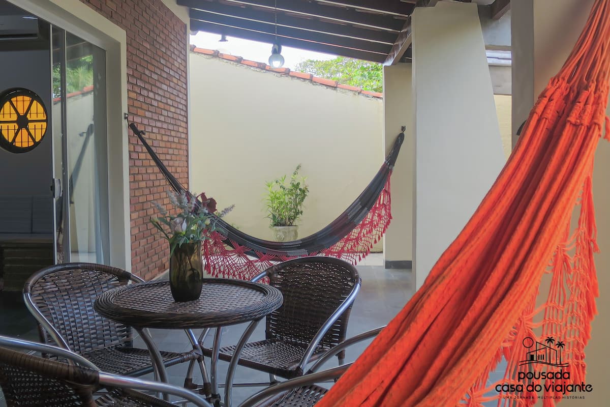A covered patio area with wicker furniture, a hammock, and a potted plant.