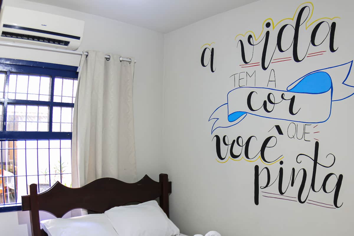 A hotel room with a bed, a wall decoration, and a window with curtains.